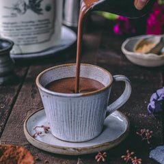 Powdered supplement in a scoop next to a glass