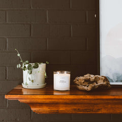 Luxurious candle in clear glass jar on light surface