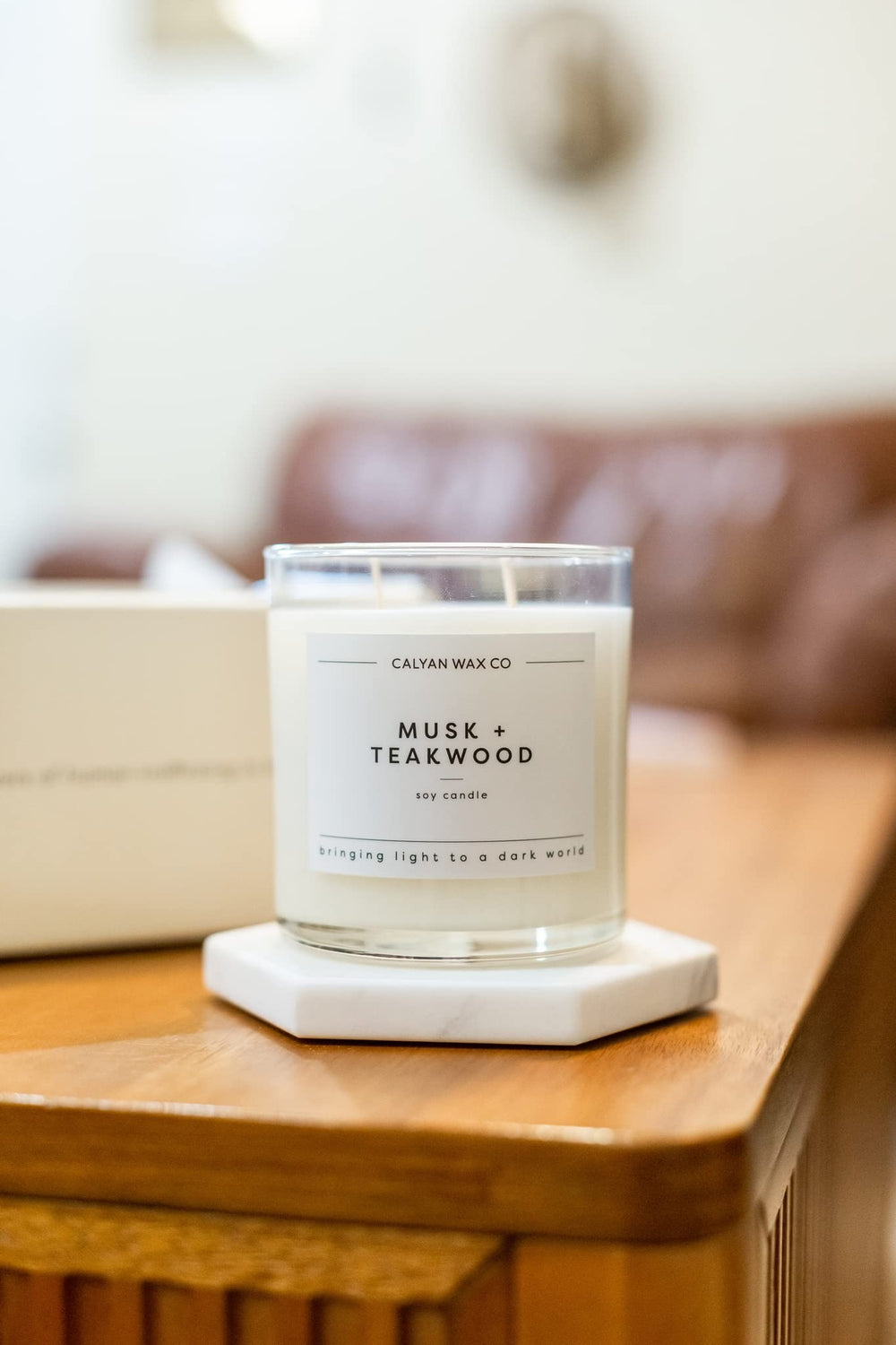 Large glass jar candle with lid on neutral backdrop