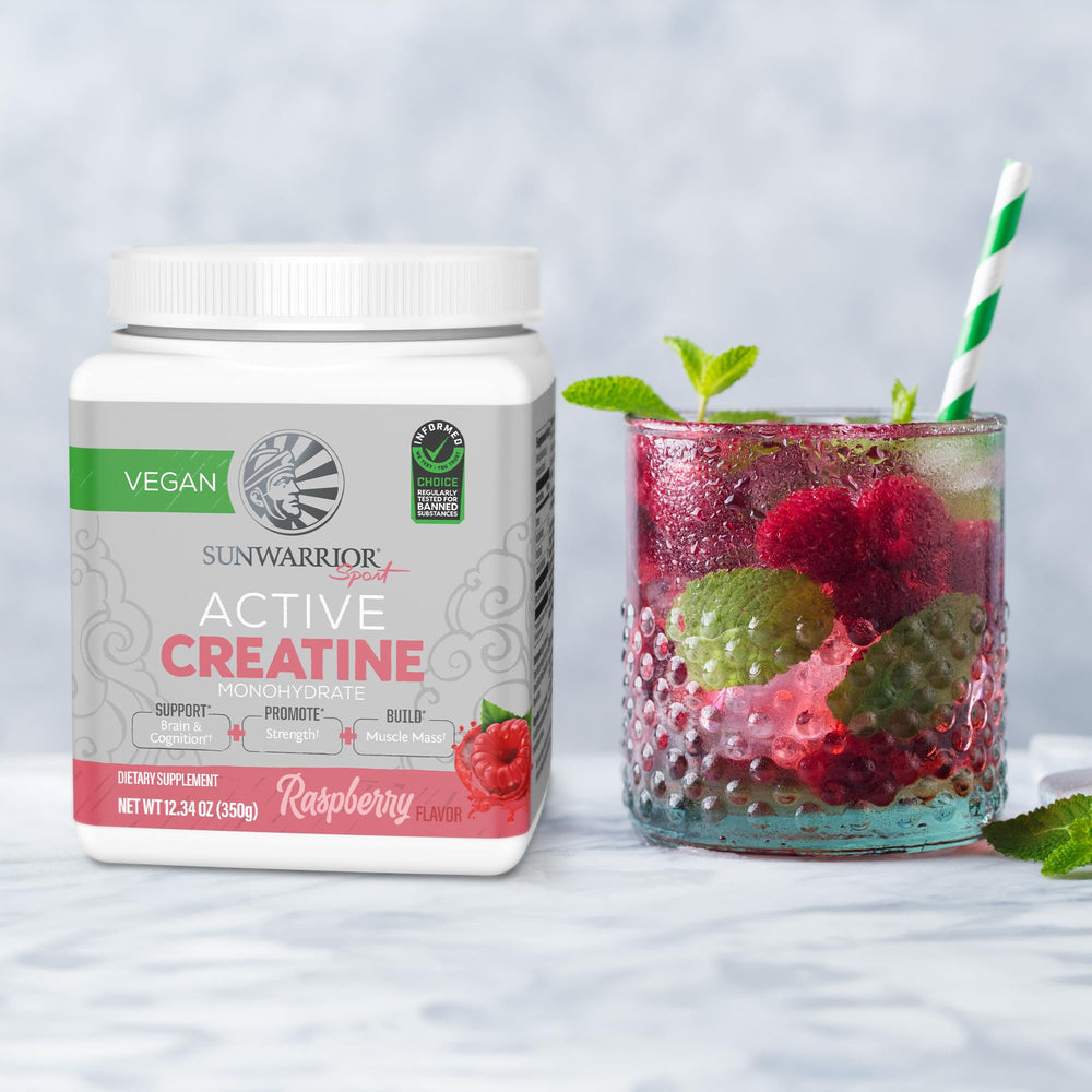 Raspberry-flavored creatine powder tub with glass and scoop