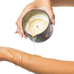 Hand pouring melted massage oil from candle