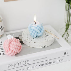 Close-up of cotton wick and pastel pink yarn detailing on candle
