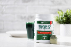 One scoop of Pur Tesai TesaiGreens powder being added to a glass of water