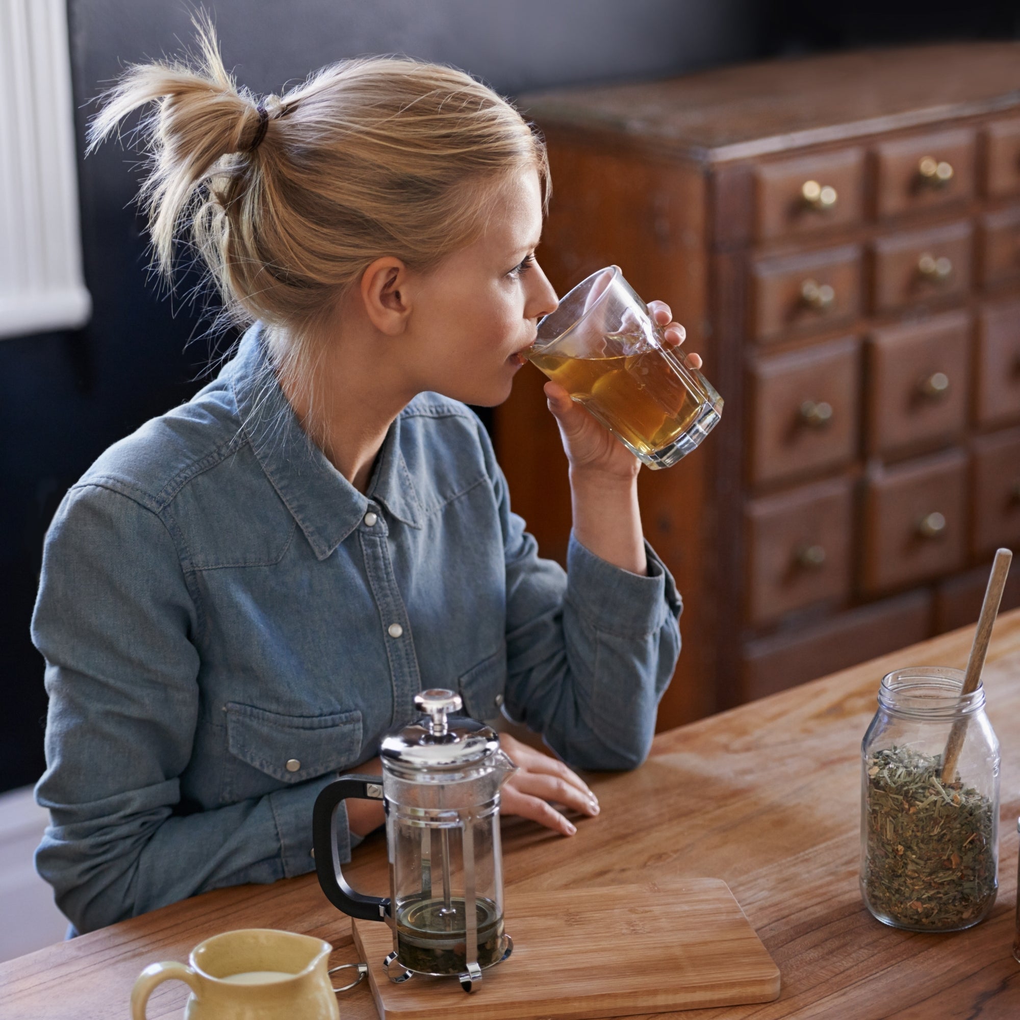 Woman preparing herbal supplements at home, highlighting natural plant-based wellness and daily herbal nutrition support