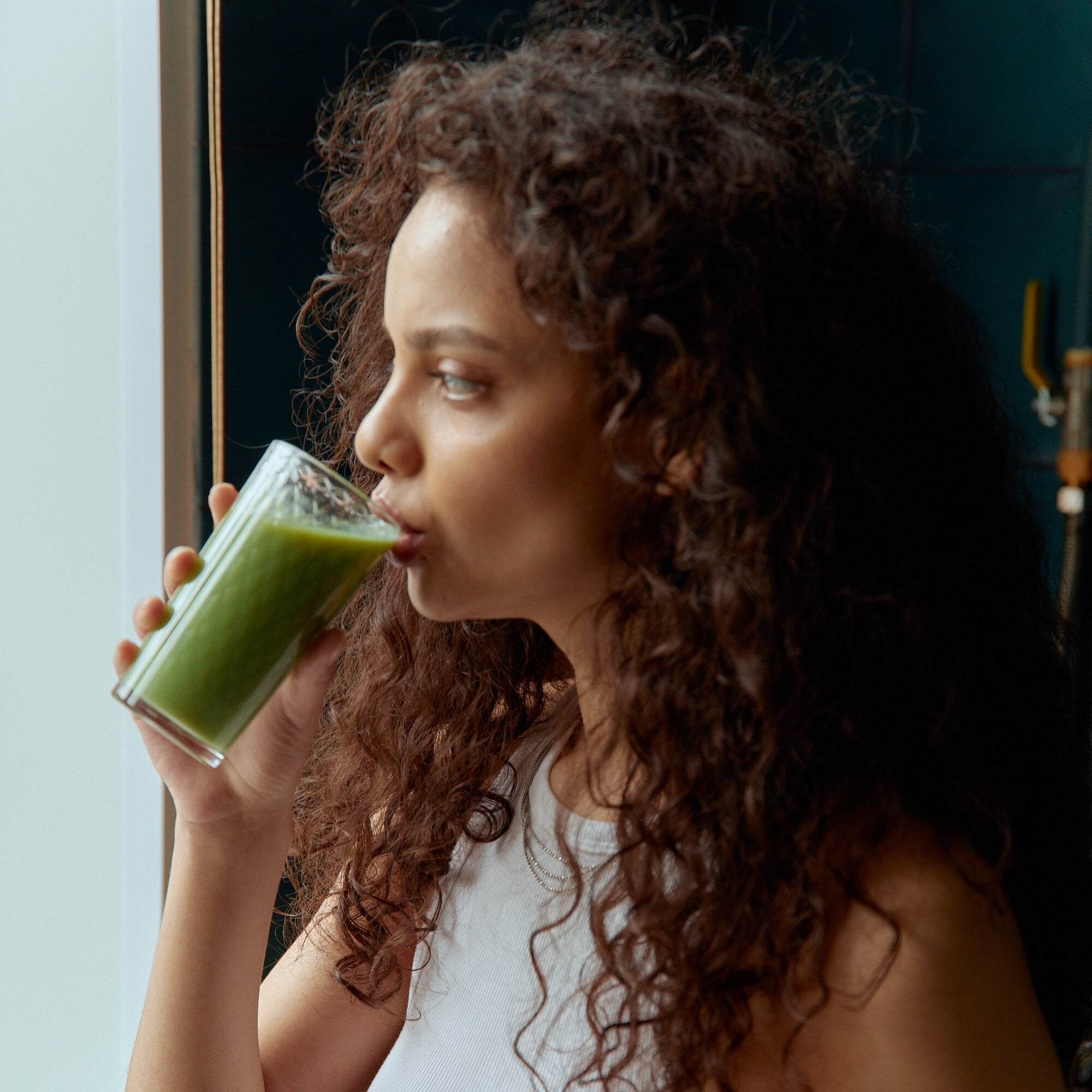 Woman drinking a green smoothie, including essential minerals that support balance, strength, and everyday wellness