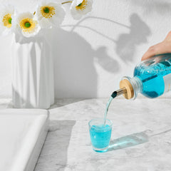 Mouthwash bottle resting on a natural bamboo tray