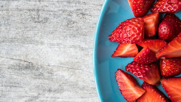 Sliced strawberries on a blue plate with a gray wooden background