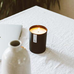 Lifestyle shot of the Aspen & Fog candle on a coffee table in a living room.