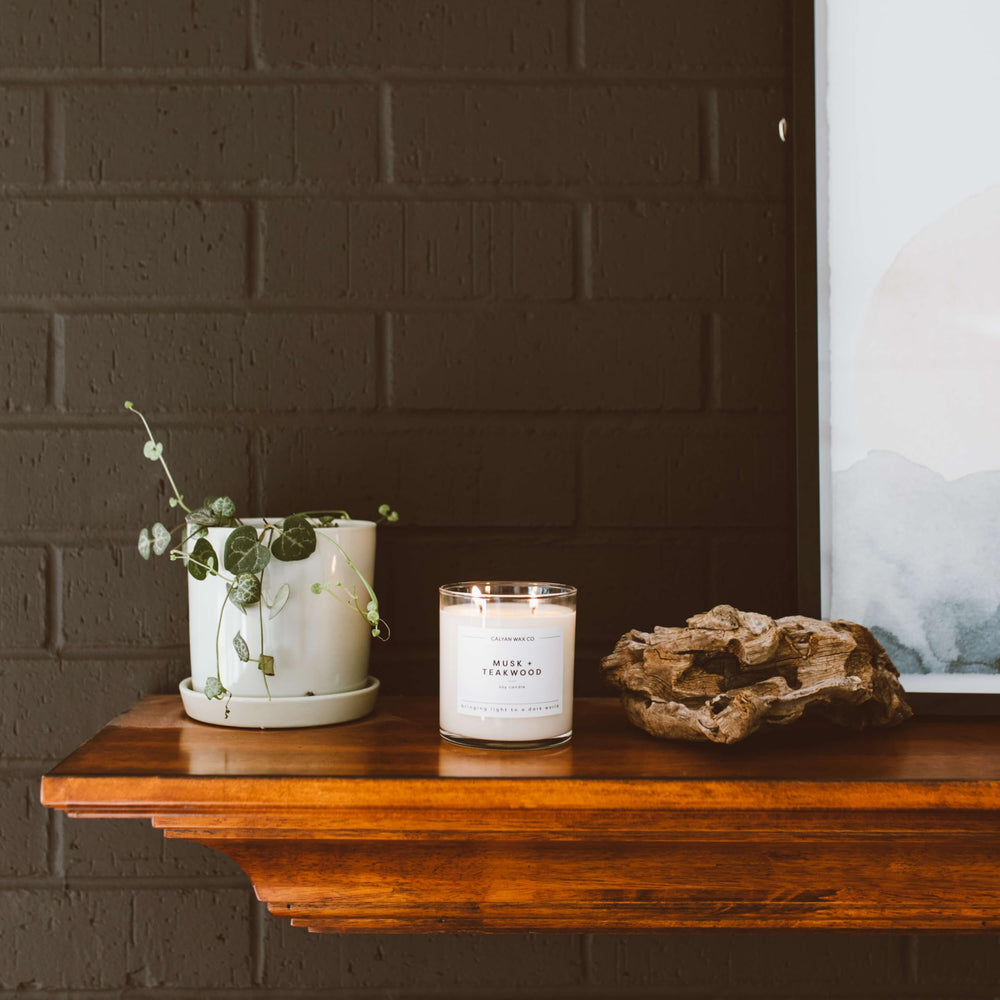 Luxurious candle in clear glass jar on light surface