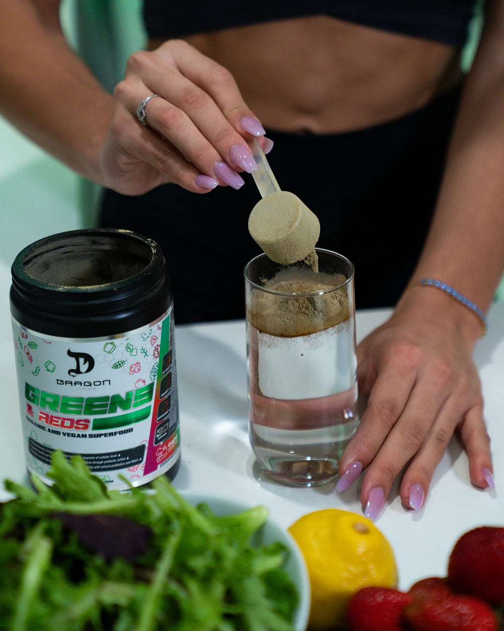 Leaning glass of lemonade with Dragon Pharma Greens & Reds scoop