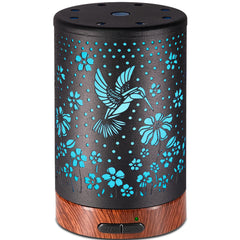 Metal-covered essential oil diffuser with hummingbird pattern on nightstand