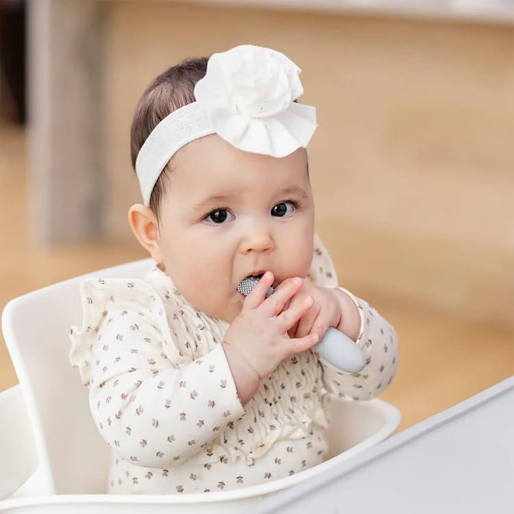 Baby's hands holding ezpz Baby-Led Toothbrush Pewter