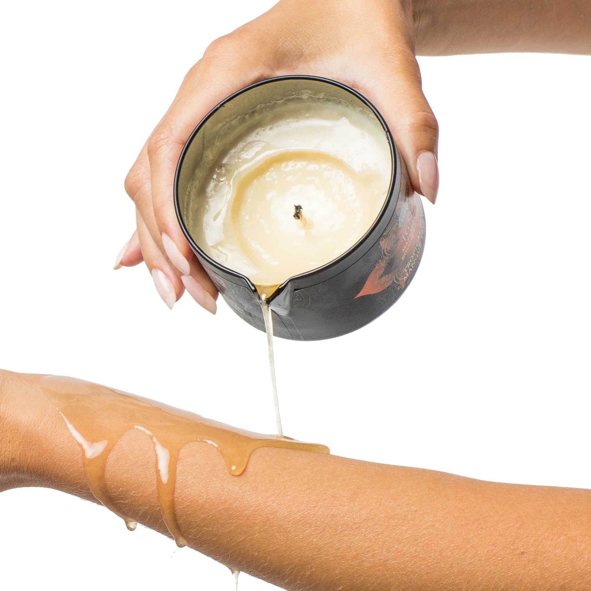 Hand pouring melted massage oil from candle