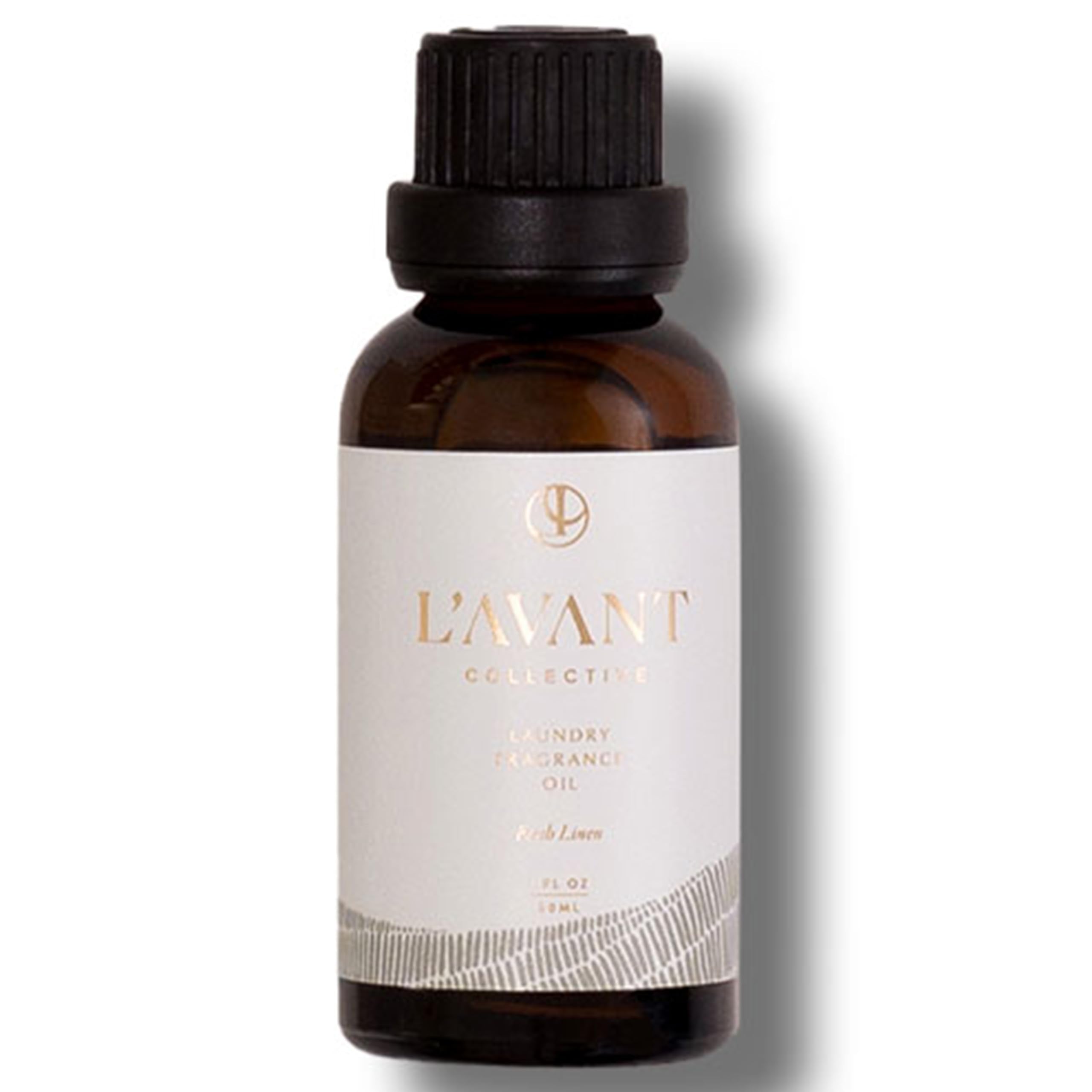 1oz bottle of L’Avant Laundry Oil beside dryer balls
