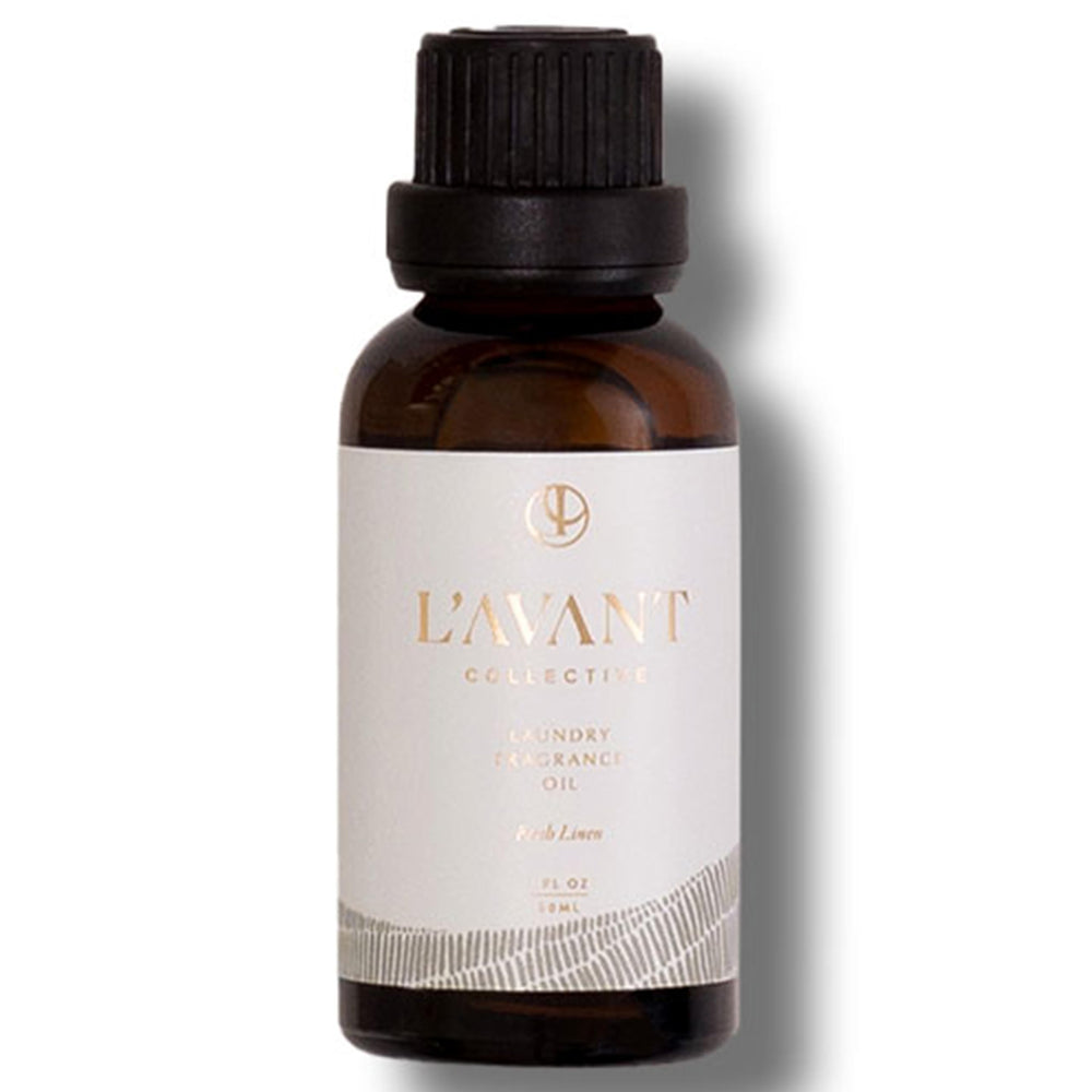 1oz bottle of L’Avant Laundry Oil beside dryer balls
