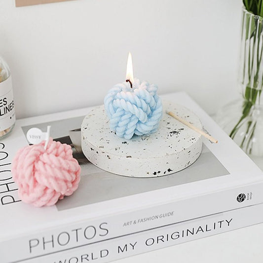 Close-up of cotton wick and pastel pink yarn detailing on candle