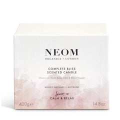 NEOM Complete Bliss candle burning in a cozy living room setting.