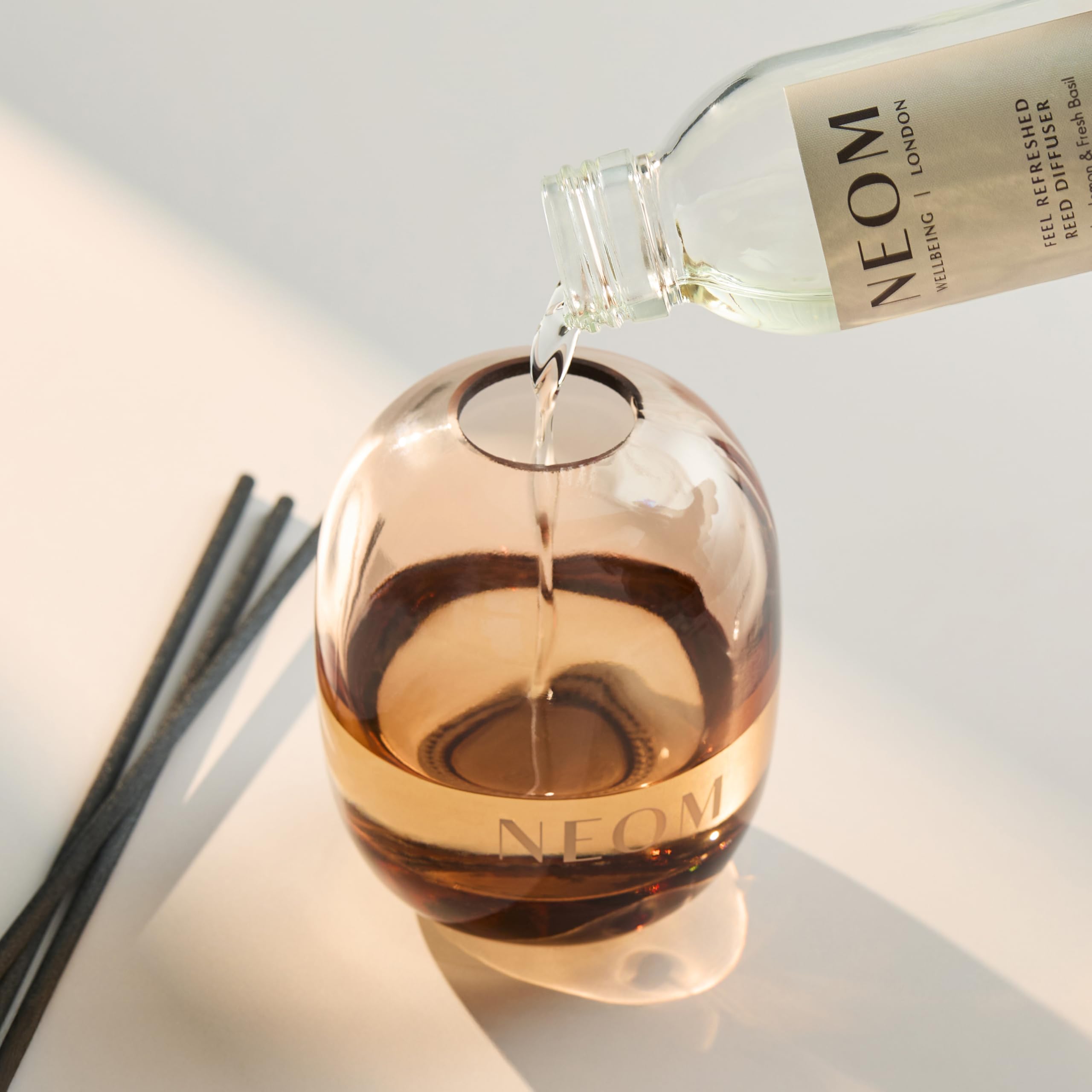 Close-up of 100ml reed diffuser refill bottle and natural reeds