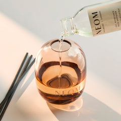 Close-up of 100ml reed diffuser refill bottle and natural reeds