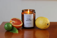 Hand-poured candle shown in a white container with amber lid