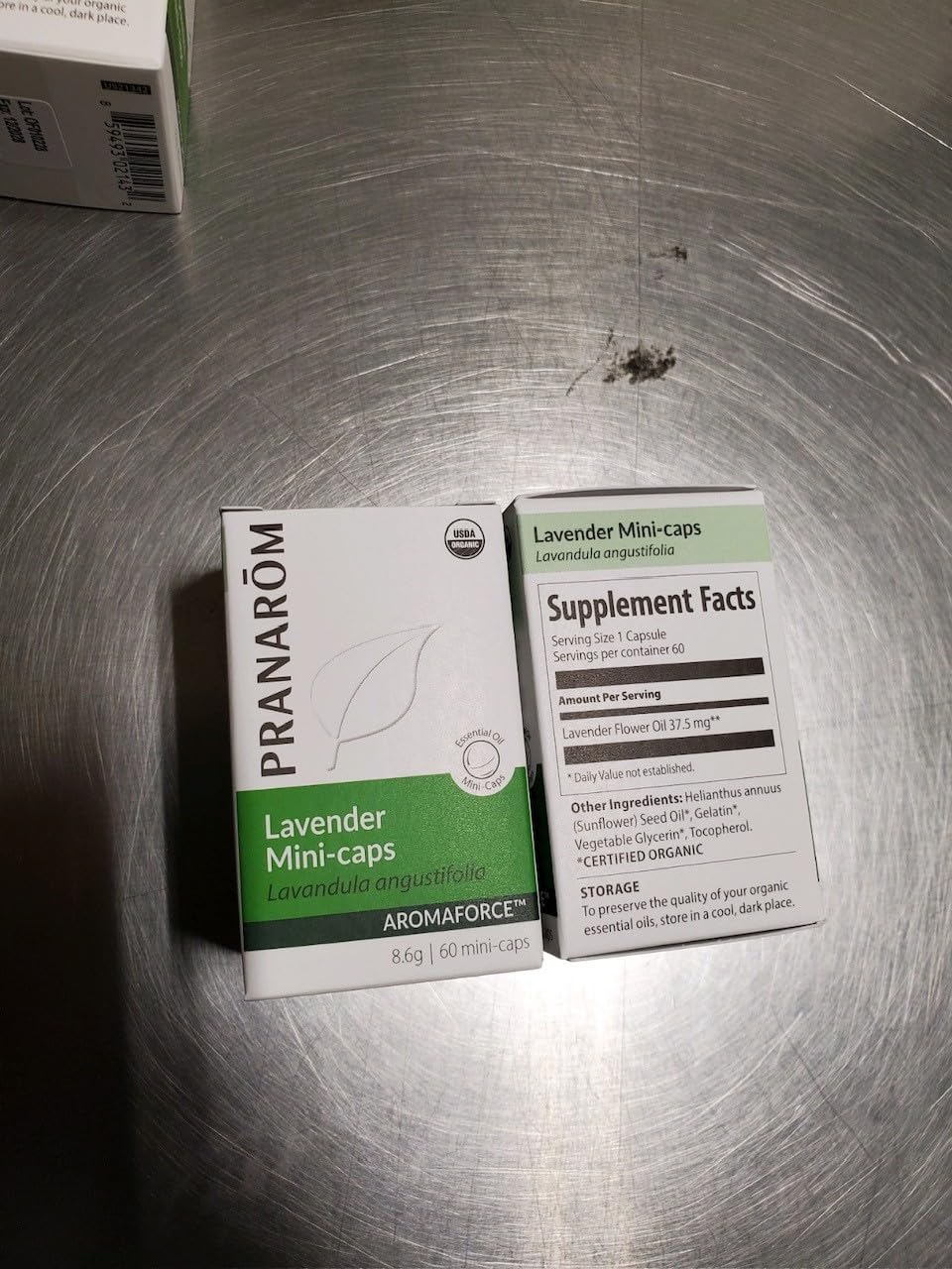 Lifestyle shot of a hand holding a Lavender Mini-Caps with a glass of water