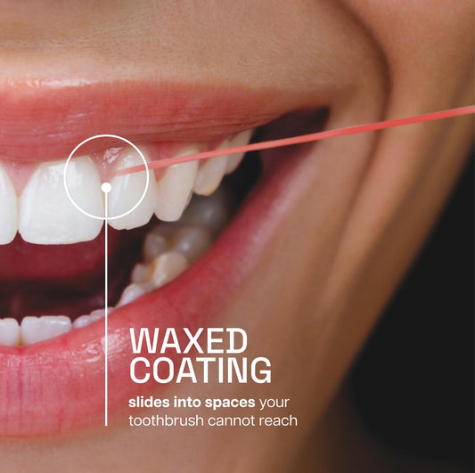 Close-up of cinnamon-flavored waxed floss sliding between teeth