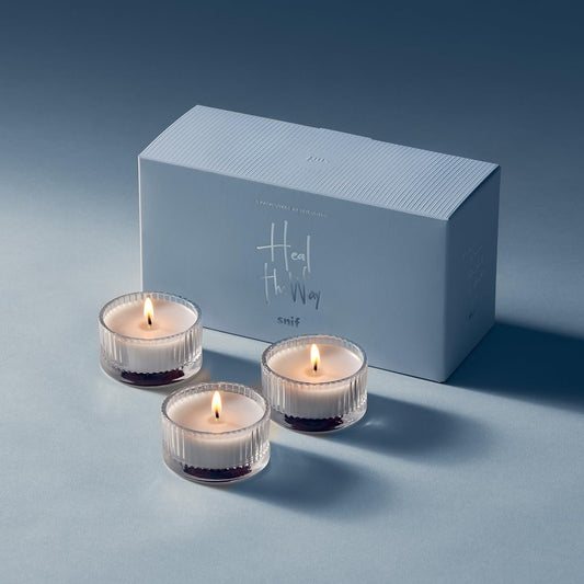Snif Heal The Way Votive unlit candle sits on wood, ready for a calming ritual.