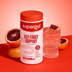 Scoop of GLP1 Daily Support powder next to glass