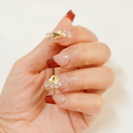 Tesytto nude base nails with gold glitter and 3D rhinestones for a luxury manicure