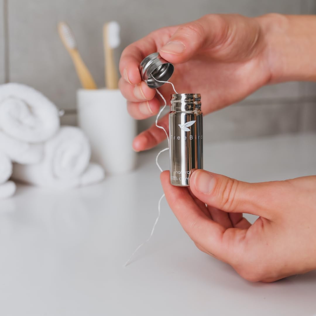 Open stainless steel floss dispenser showing 33-yard silk spool