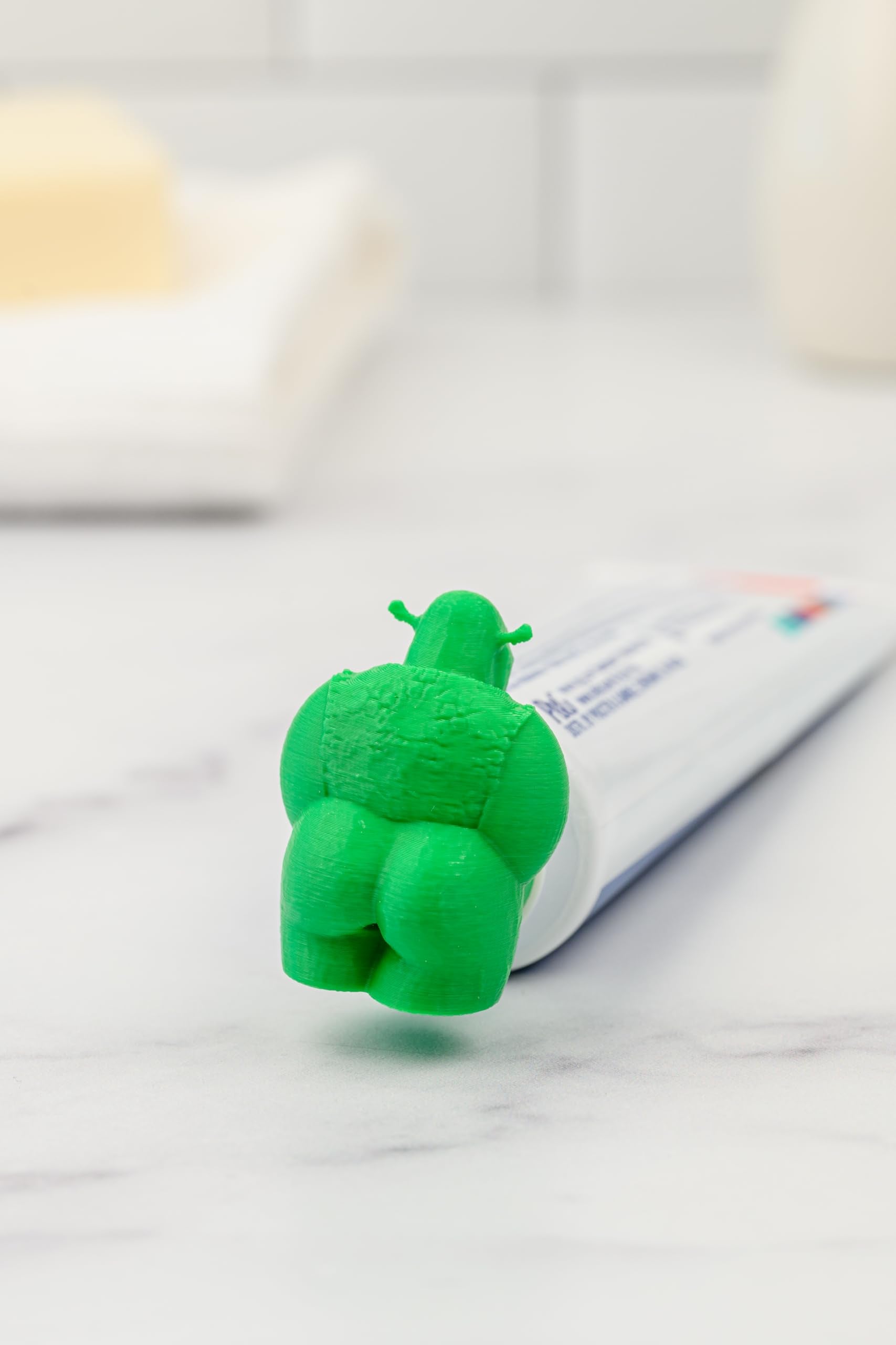 Shrek pooping toothpaste topper showing adapters for Crest and Colgate