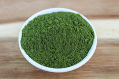 Wheatgrass powder being added to a smoothie
