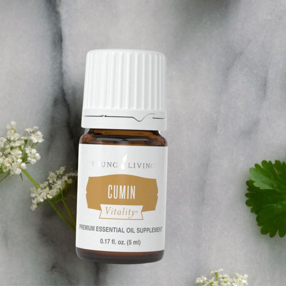 Young Living Cumin Vitality bottle beside fresh cumin seeds to illustrate detox aroma.