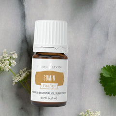 Young Living Cumin Vitality bottle beside fresh cumin seeds to illustrate detox aroma.